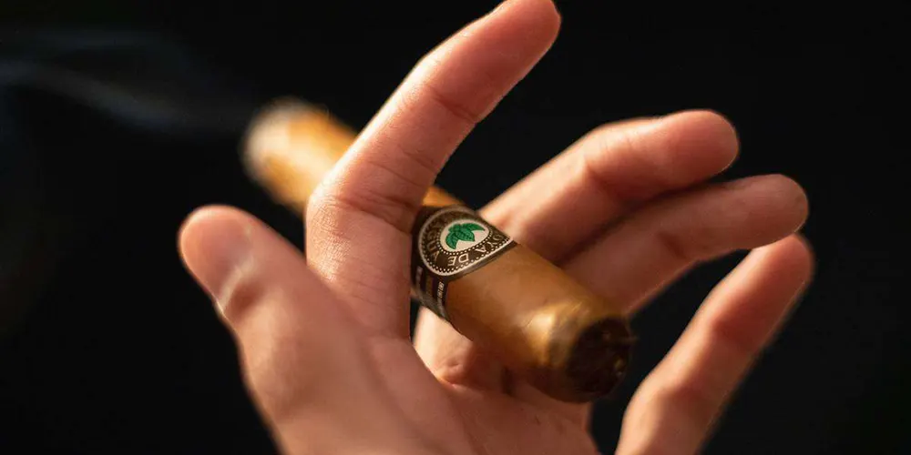 Rauchende Zigarre in der Hand